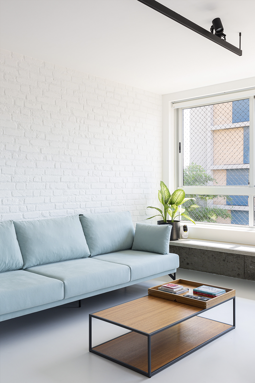 sala de estar com sofá azul e parede de tijolinho branco
